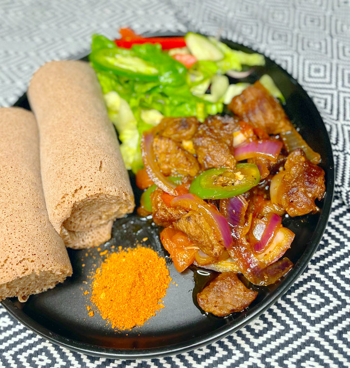 Ethiopian Food - Beef tibes served with a side of injera and salad 